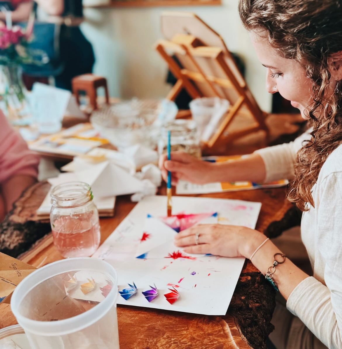 Woman watercoloring painting on origami flowers.